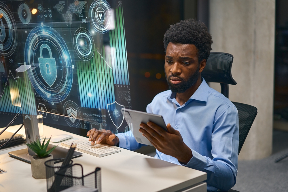 FocusedManAnalyzingCybersecurityDataOnScreenInModernOffice Focused Man Analyzing Cybersecurity Data On Screen In Modern Office Setting