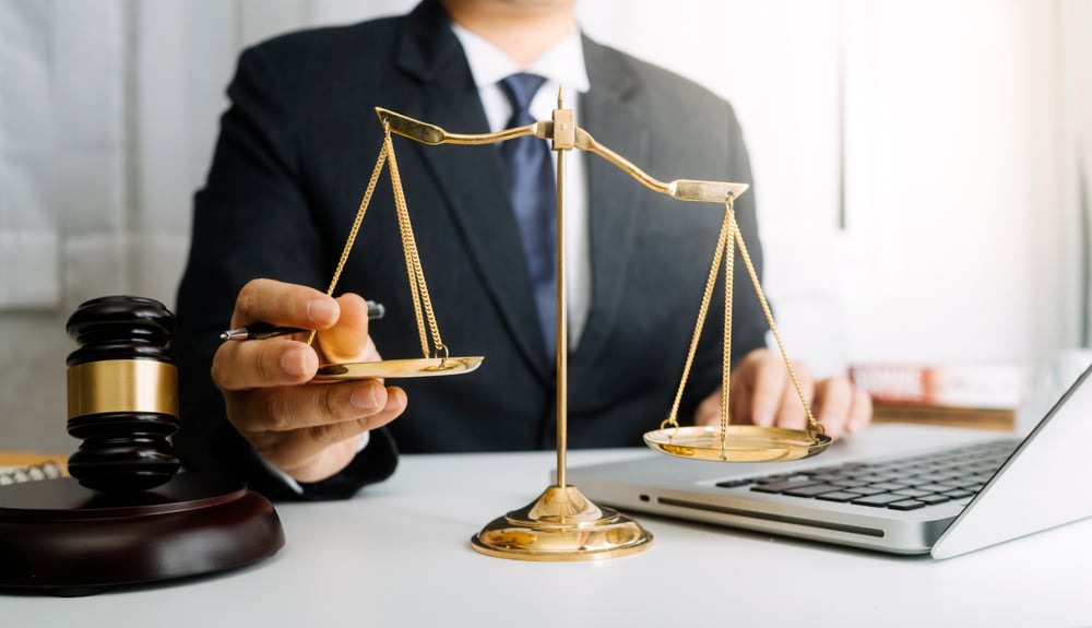BusinessAndLawyersDiscussingContractPapersWithBrassScaleOn Business and lawyers discussing contract papers